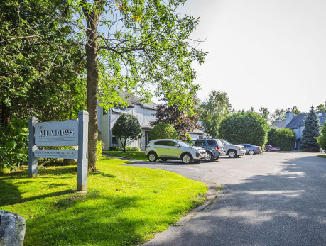 Exterior view of The Meadows condos in Toronto, featuring a sign and parking area, showcasing