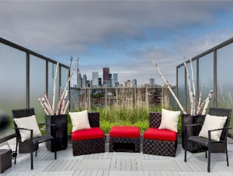 Luxury condo balcony overlooking the Toronto skyline, showcasing outdoor seating and a vibrant rooftop garden